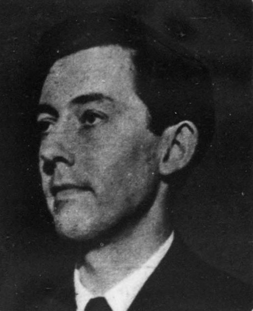Fotografía en blanco y negro del rostro de un hombre joven de perfil de tres cuartos, con el pelo corto peinado hacia atrás y la mirada hacia la derecha