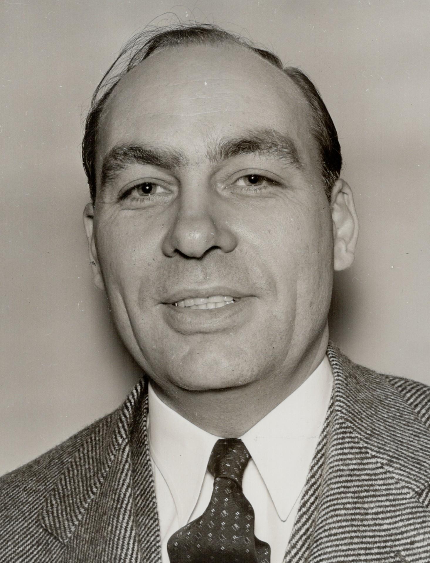 Retrato fotográfico de George Gallup, de medio cuerpo, con traje y gafas