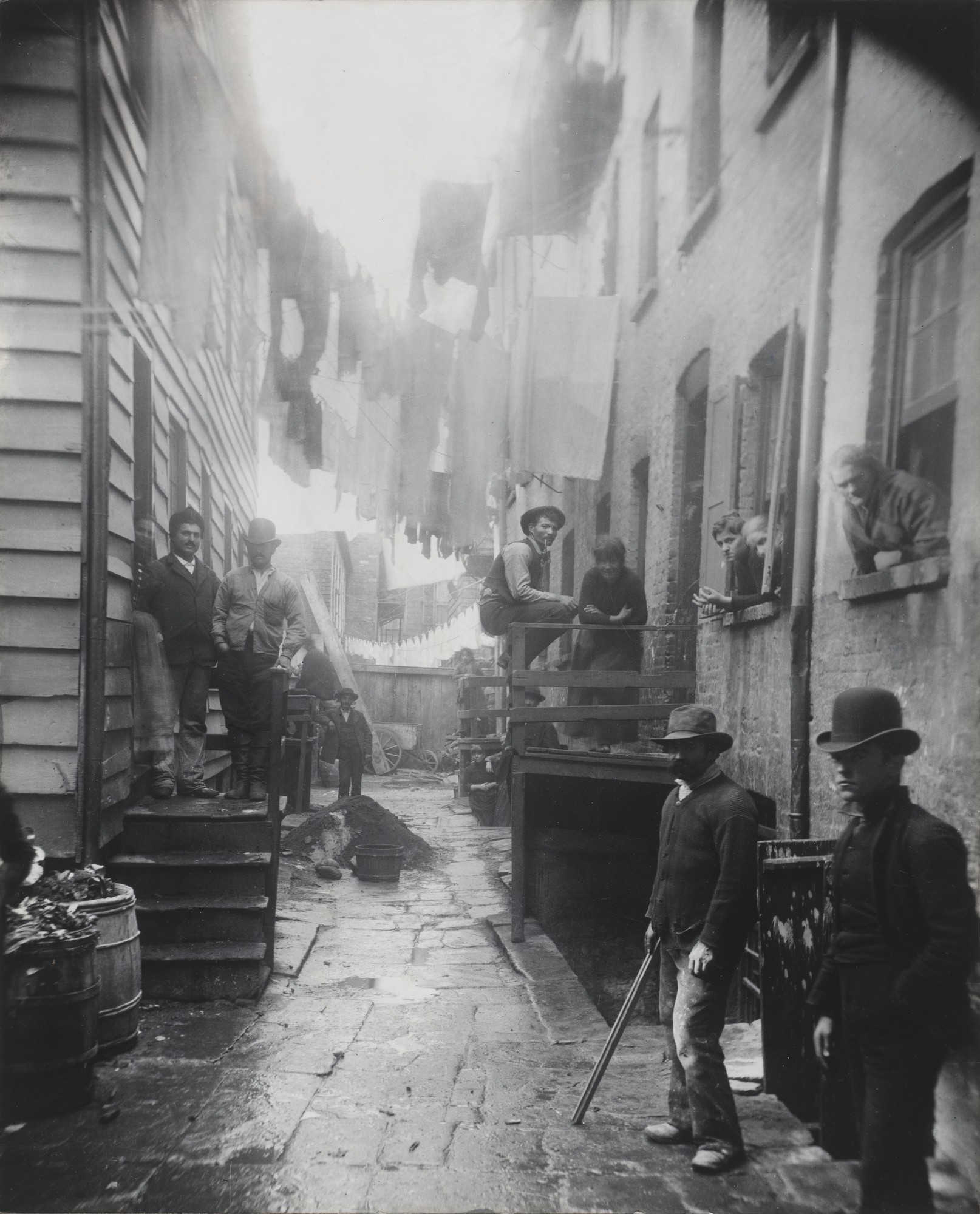 Fotografía de 1888 de un callejón oscuro de Mulberry Street, en el Lower East Side de Nueva York, con varias personas en el pasaje